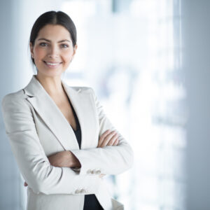 A woman in white jacket standing with her arms crossed.