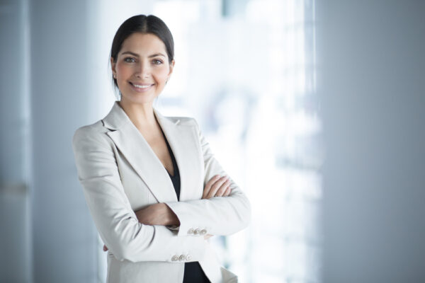 A woman in white jacket standing with her arms crossed.