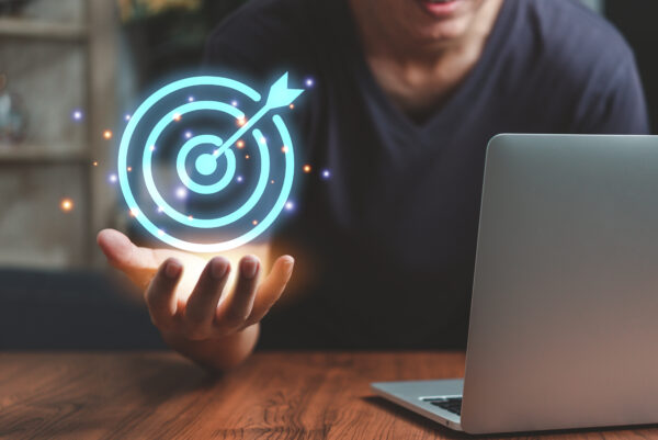 A person holding a laptop and a glowing target.